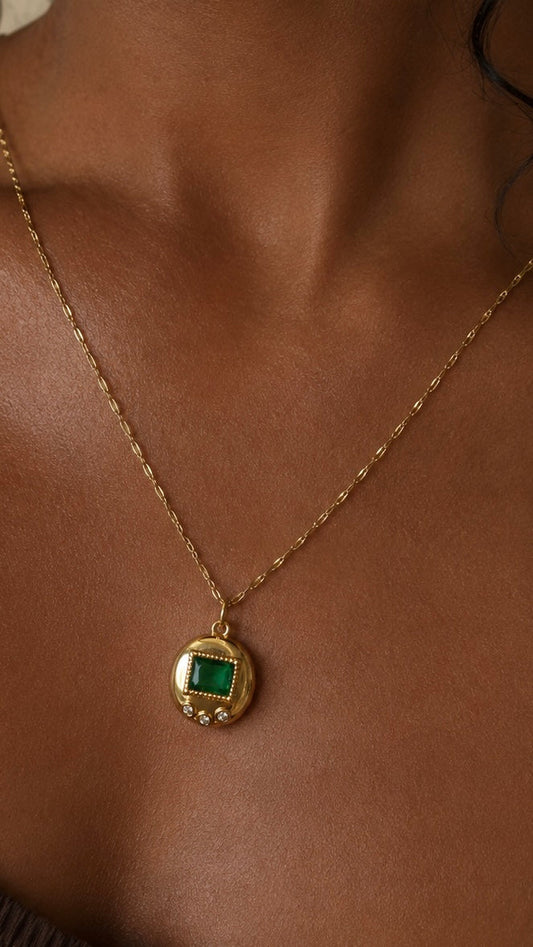 Gold digital pet charm necklace with a green gemstone worn on a gold chain.